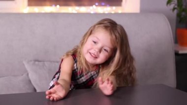 Gri odada Mandarin Clementine olan kırmızı kareli elbiseli sevimli küçük kız. Yeni yıl, çocukluk, Noel. Tam HD görüntü.
