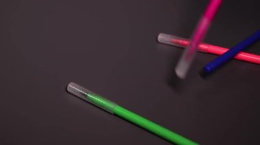 Siyah arkaplanda parlak renkli işaretler var. Sanat, acı, yazı, kırtasiye, keçeli kalem. Yüksek kaliteli FullHD görüntüler