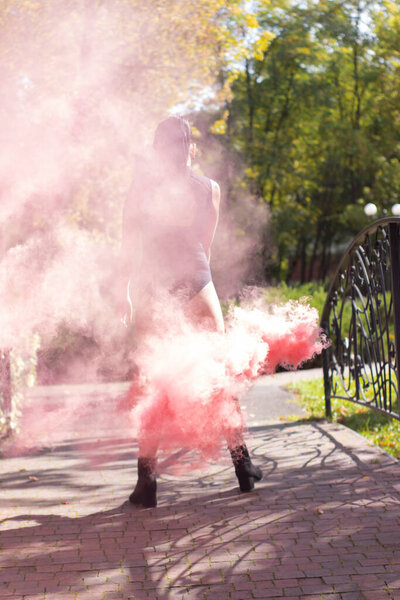 unrecognizable slim girl brunette in black bodysuit with bright pink smoke bomb. dancing, having fun. color powder. spring, summer, autumn. High quality photo