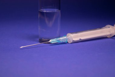 Aşı şişesi şişesinde etiket yok, şırınga iğnesi var. Mavi arka planda izole edilmiş. Koronavirüs aşısı COVID-19 'un gelişimi. Tedavi. Araştırmada dünya yarışı. Boşluğu kopyala