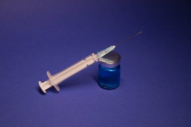 Aşı şişesi şişesinde etiket yok, şırınga iğnesi var. Mavi arka planda izole edilmiş. Koronavirüs aşısı COVID-19 'un gelişimi. Tedavi. Araştırmada dünya yarışı. Boşluğu kopyala