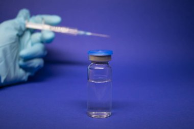 Koronavirüs aşısı COVID-19 'un gelişimi. Şişe şişesinin yanında etiketsiz mavi eldiven iğnesiyle tıbbi şırınga. Mavi arka planda izole edilmiş. Tedavi. Boşluğu kopyala