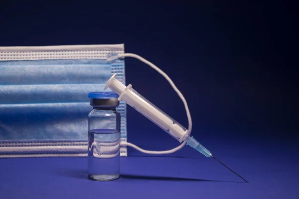파란색 마스크 근처에 라벨이 피알과 바늘이 의료용 주사기 배경에 고립되어 — 스톡 사진
