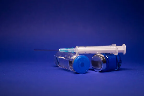 两个没有标签的透明疫苗瓶塞 医用注射器注射针 被蓝色背景隔离 Coronavirus疫苗Covid 19的开发 世界竞赛的研究 复制空间 — 图库照片