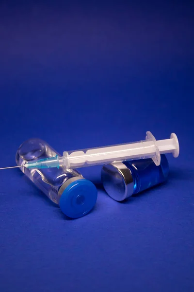 Etiketsiz Iki Şeffaf Aşı Şişesi Şırınga Iğnesi Mavi Arka Planda — Stok fotoğraf
