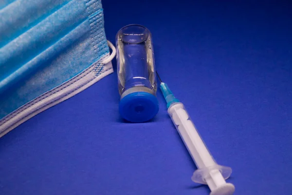 파란색 마스크 근처에 라벨이 피알과 바늘이 의료용 주사기 배경에 고립되어 — 스톡 사진
