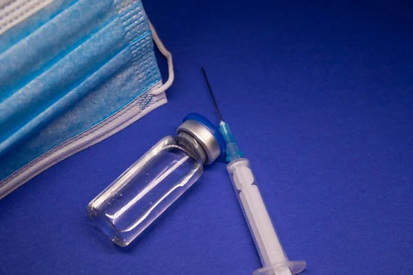 Mavi Tıbbi Maskenin Yanında Etiketsiz Aşı Şişesi Şişesi Enjeksiyonlu Tıbbi — Stok fotoğraf
