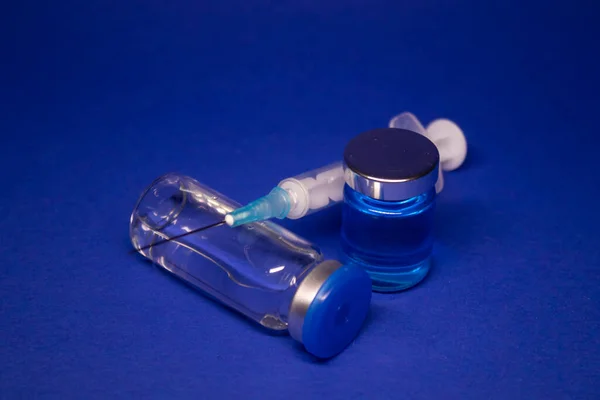 Etiketsiz Iki Şeffaf Aşı Şişesi Şırınga Iğnesi Mavi Arka Planda — Stok fotoğraf