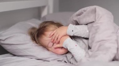  Gri yatak odasında yatan sevimli küçük kız. Sabah rutini, çocukluk, kız. Tam HD görüntüler