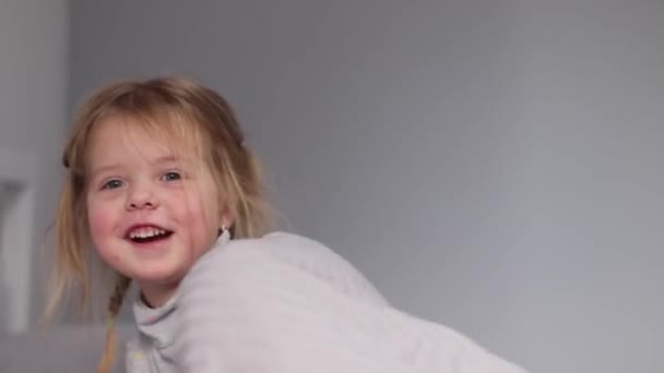 Encantadora niña divirtiéndose, saltando en la cama en el dormitorio gris. rutina de la mañana, infancia, hija. Imágenes de FullHD — Vídeos de Stock