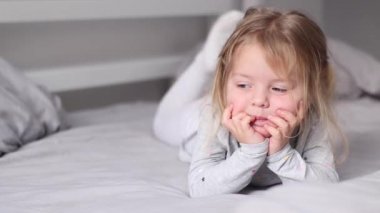  Gri yatak odasında yatan sevimli küçük kız. Sabah rutini, çocukluk, kız. Tam HD görüntüler