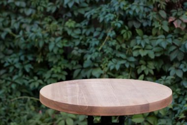 Yeşil yapraklı sarmaşık duvarının arkasındaki tahta masa yüzeyi. Boşluğu kopyala