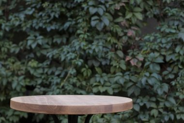 Yeşil yapraklı sarmaşık duvarının arkasındaki tahta masa yüzeyi. Boşluğu kopyala