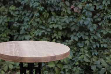 Yeşil yapraklı sarmaşık duvarının arkasındaki tahta masa yüzeyi. Boşluğu kopyala