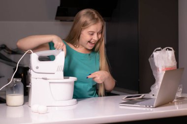 Sarışın bir kadın video blogcu mutfakta yemek pişiriyor ve filme çekiyor, online öğreniyor ya da uzaktan aşçılık dersi alıyor. Canlı yayındayız. yemek pişirme dersi