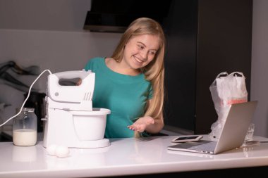 Sarışın bir kadın video blogcu mutfakta yemek pişiriyor ve filme çekiyor, online öğreniyor ya da uzaktan aşçılık dersi alıyor. Canlı yayındayız. yemek pişirme dersi