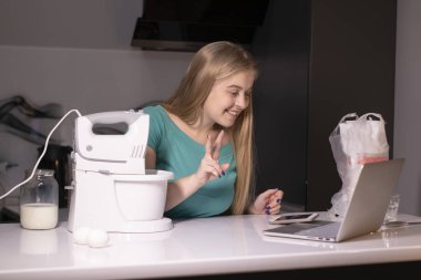 Sarışın bir kadın video blogcu mutfakta yemek pişiriyor ve filme çekiyor, online öğreniyor ya da uzaktan aşçılık dersi alıyor. Canlı yayındayız. yemek pişirme dersi