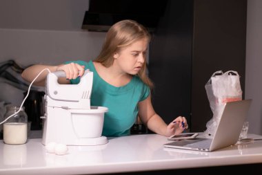 Sarışın bir kadın video blogcu mutfakta yemek pişiriyor ve filme çekiyor, online öğreniyor ya da uzaktan aşçılık dersi alıyor. Canlı yayındayız. yemek pişirme dersi