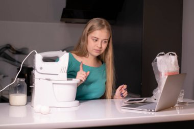 Sarışın bir kadın video blogcu mutfakta yemek pişiriyor ve filme çekiyor, online öğreniyor ya da uzaktan aşçılık dersi alıyor. Canlı yayındayız. yemek pişirme dersi