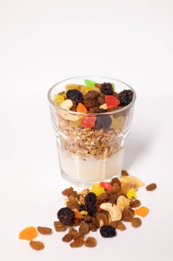 Yoğurt ve şekerli bardakta müsli tatlı ya da beyaz arka planda izole edilmiş ahududu ile kurutulmuş meyve. Yakınlarda kuru üzüm, fındık ve şekerli meyve var. Kahvaltı gevreği.