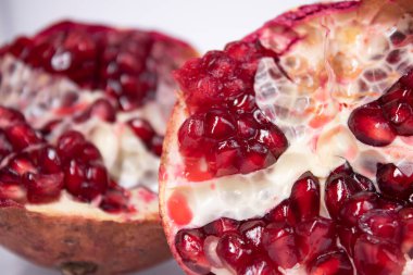 olgun taze dilimlenmiş nar meyvesi ve beyaz arka planda izole kırmızı tohumlar.