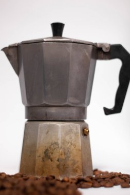 Gayzer kahve makinesi ya da moka demliği beyaz arka planda izole edilmiş ve kahve çekirdekleri yakınında..