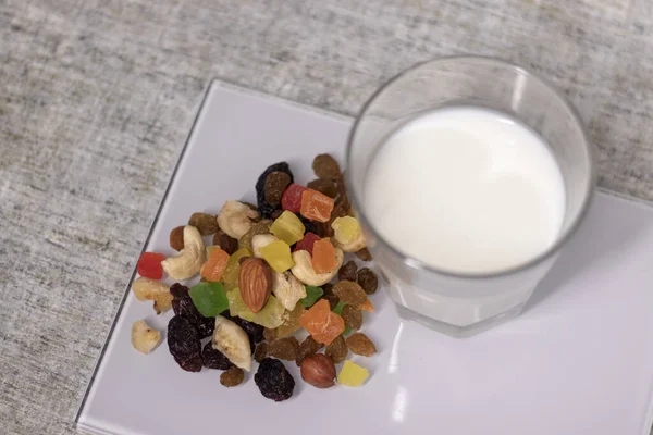 glass of milk near dried fruits, candied fruits, raisins, nuts. healthy breakfast snack.