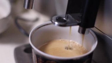 Evdeki bir fincana kahve dolduran otomatik bir kahve makinesini kapat.