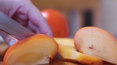 Kadınlar taze turuncu hurma dilimlerini tahta kesme tahtasıyla keserler. diyet. egzotik tropikal meyveler