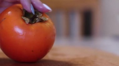 Kadınlar taze turuncu hurma dilimlerini tahta kesme tahtasıyla keserler. diyet. egzotik tropikal meyveler