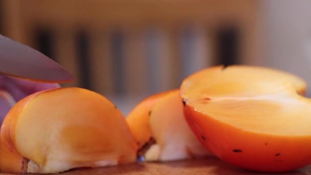 女性の手のスライスは 木のまな板に熟した新鮮なオレンジ柿 食事よ 熱帯のエキゾチックな果物 — ストック動画