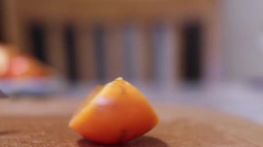 Tahta kesme tahtasında dilimlenmiş taze portakal hurması. diyet. egzotik tropikal meyveler