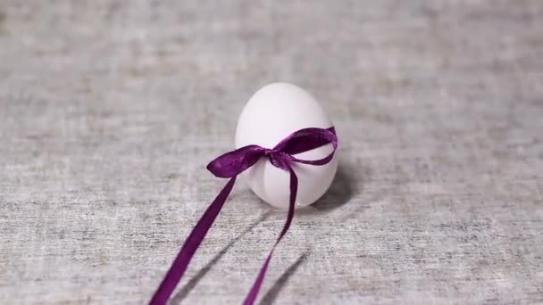 Куриное Белое Яйцо Связанное Фиолетовым Бантом Ленты Сером Фоне Весна — стоковое видео