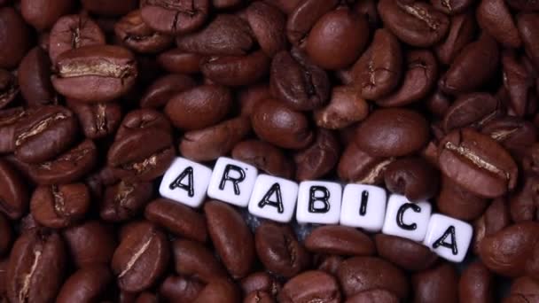 Скольжение Жареным Кофейным Зеренам Словом Arabica Написанным Маленькими Белыми Кубиками — стоковое видео