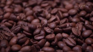 Kavrulmuş kahve çekirdeğini yakın plan. Kokulu kahve çekirdekleri yukarıdan yavaş çekimde kahve çekirdekleri üzerine dökülüyor. Arabistan, Robusta