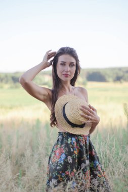 Sahada göğüslerini hasır bir şapkayla örten üstsüz esmer kadın.