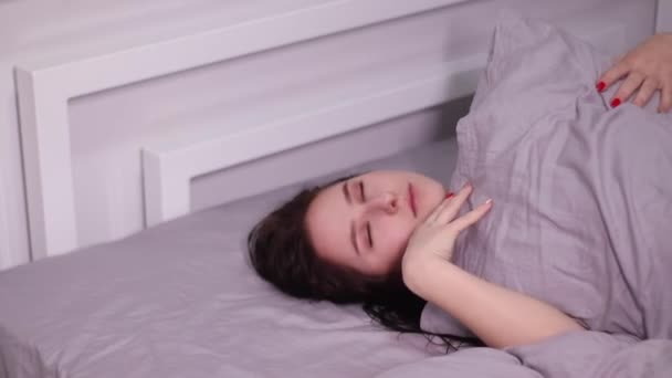 灰色のシーツのベッドで官能的な美しいブルネットの女性は 夢と思考を持って寝て — ストック動画