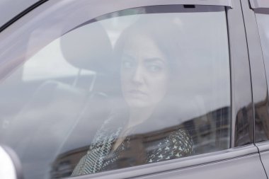 Siyah bir arabada gri kareli elbiseli çekici bir esmerin portresi. Otomobildeki kız. iş kadını