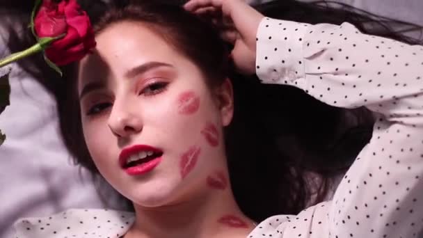 Seksowna brunetka z pocałunkami, ślady szminki na twarzy i szyi, z czerwoną różą. dziewczyna, randka, relashionship — Wideo stockowe