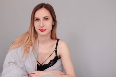 Gri çarşaflı ve battaniyeli siyah iç çamaşırlı güzel kızıl saçlı kadının portresi..