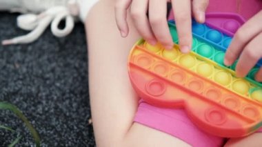 Çocuk tanınmayan eller silikon hareketli oyun oynuyorlar. Duyusal oyuncak patlat. Gökkuşağı yumuşak silikon kabarcıkları. Anksiyete, stres önleyici, zihinsel sağlık konsepti. Stres önleyici oyun popit. yavaş çekim