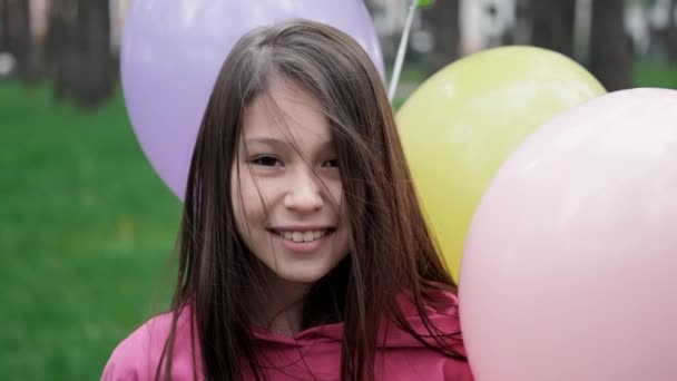 Sladká brunetka dospívající dívka v růžové mikině baví s horkovzdušnými balónky. Veselé letní dny, prázdniny, prázdniny. zpomalený pohyb — Stock video