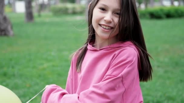 Söt brunett tonåring flicka i rosa tröja har kul med varmluft ballonger. Glada sommardagar, semester, semester. slow motion — Stockvideo