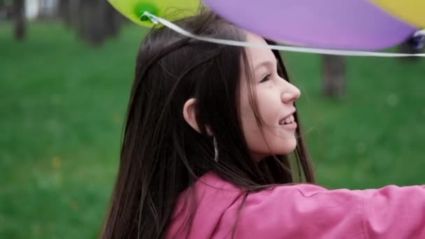 Sweet brunette teenage girl in pink sweatshirt having fun with hot air balloons. happy summer days, vacation, holidays. slow motion — Stock Video