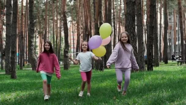 カラフルな風船で屋外の素敵な子供たち 風船を手に緑の芝生の上を走る幸せな子供たち 自由の概念子供の夢幸せな家族 スローモーション — ストック動画