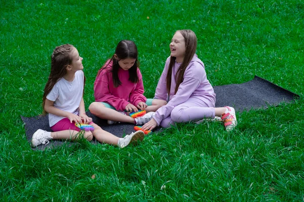 Três Adolescentes Brincam Com Brinquedo Sensorial Moderno Pop Livre Grama — Fotografia de Stock