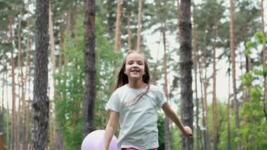Güzel anaokulu kızı dışarıda sıcak hava balonlarıyla oynarken eğleniyor. Tatil günleri, parti, doğum günü, kutlama. Mutlu çocuklar. yavaş çekim