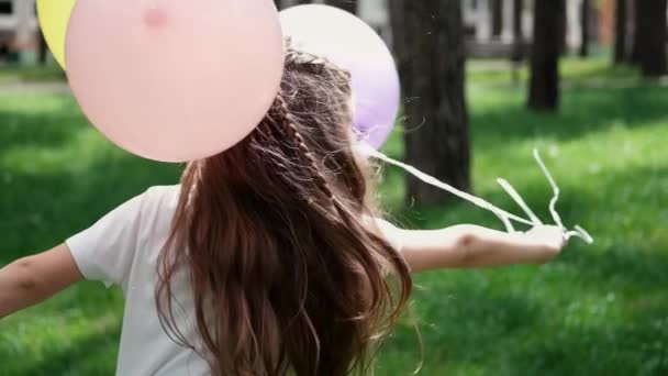 Menina pré-escolar bonita se divertindo brincando com balões de ar quente ao ar livre. Hollidays, festa, aniversário, celebração. crianças felizes. câmara lenta — Vídeo de Stock