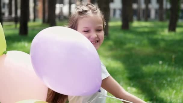 Ganska förskola flicka har kul att leka med varmluft ballonger utomhus. Hollidays, fest, födelsedag, fest. lyckliga barn. slow motion — Stockvideo