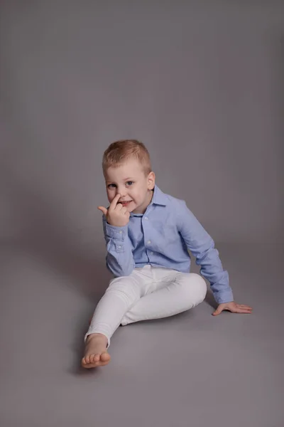 Menino Loiro Pré Escolar Calças Brancas Camisa Azul Fundo Cinza — Fotografia de Stock